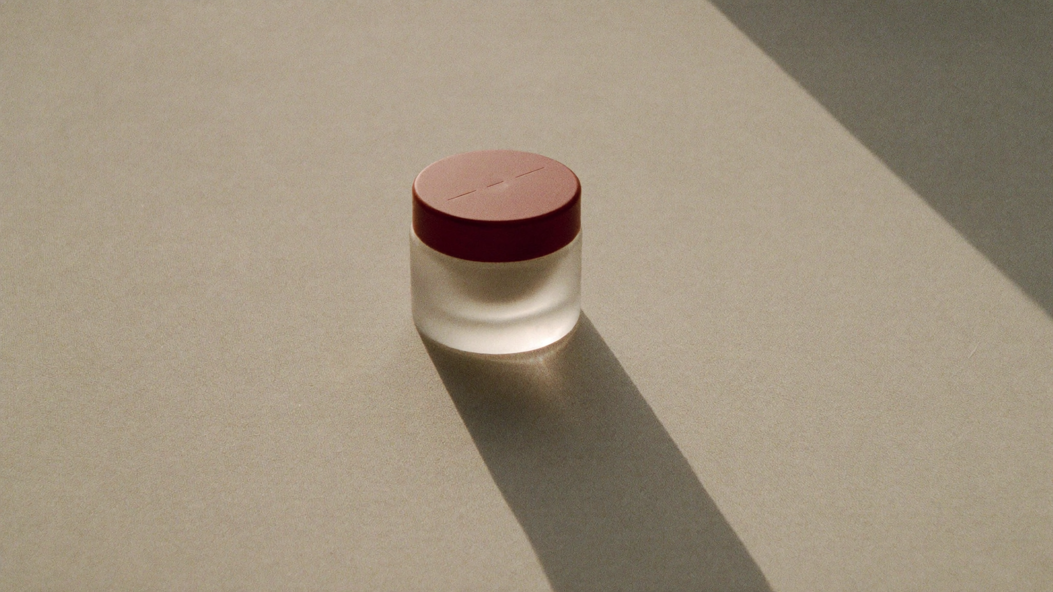 A small delicate jar catching soft dawn light on a pale linen surface
