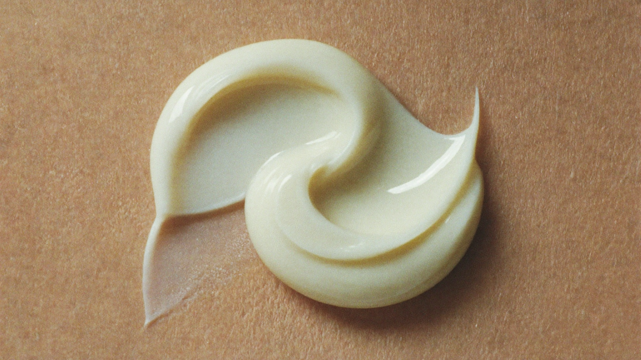 Soft cream texture swirled gently across a warm bone surface in even light